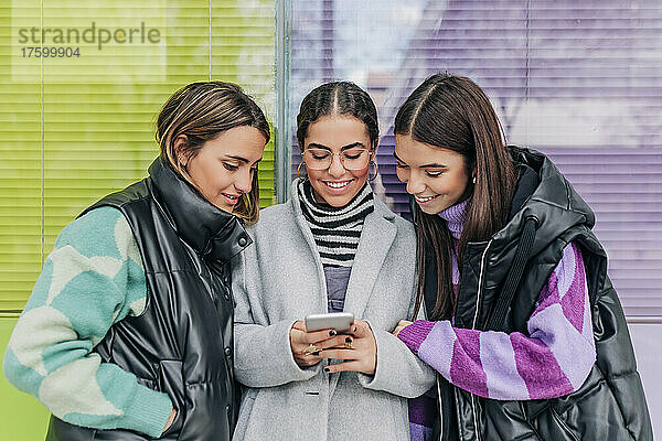 Young woman sharing smart phone with friends