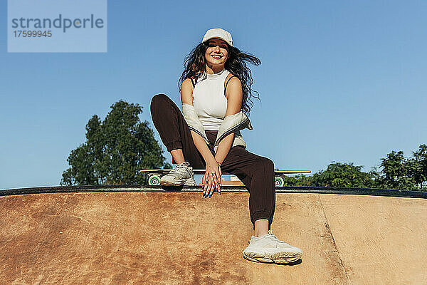 Lächelnde Frau im Skateboardpark an einem sonnigen Tag