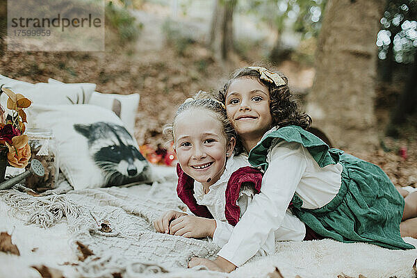 Girl lying on smiling friend at forest in Christmas