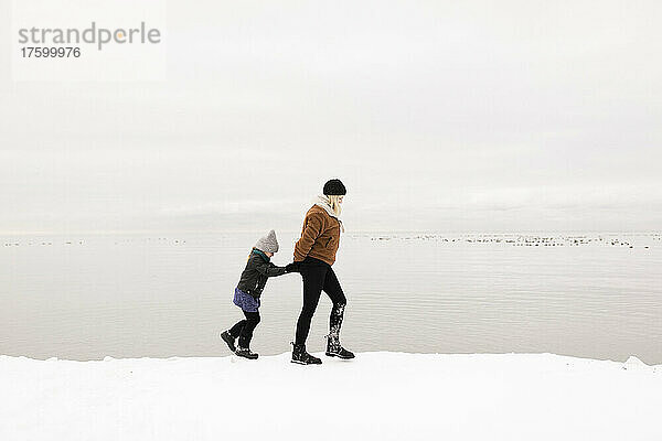 Mutter und Tochter gehen im Winter am See entlang