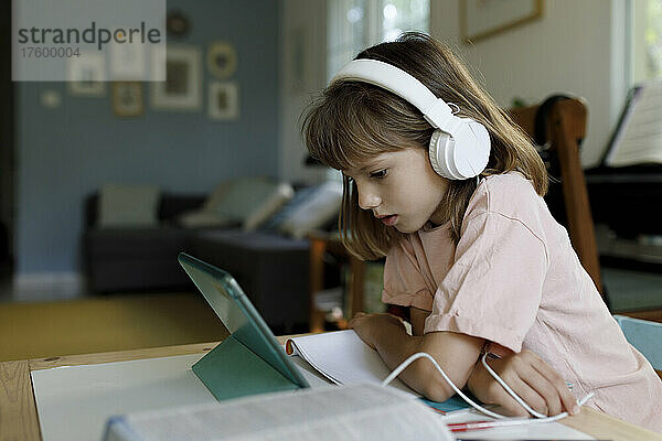 Mädchen mit Kopfhörern beim E-Learning per Tablet-PC zu Hause