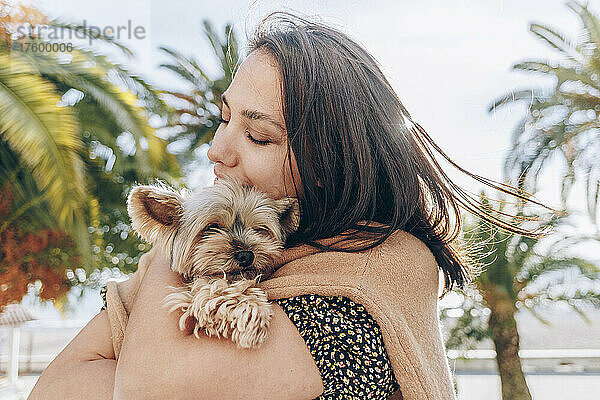 Woman hugging Yorkshire Terrier on sunny day