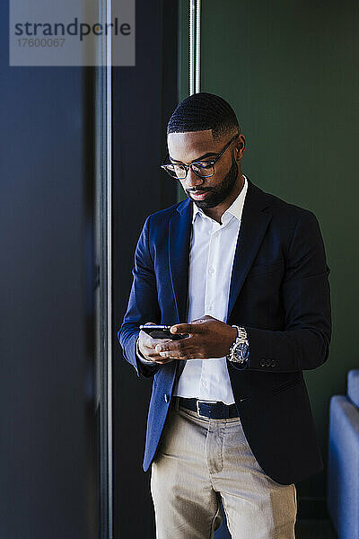Geschäftsmann mit Brille nutzt Smartphone im Büro