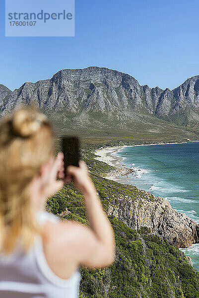 Frau fotografiert Berge mit dem Handy