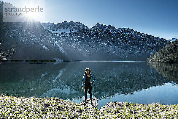 Frau mit der Hand auf der Hüfte blickt über den Plansee auf die Ammergauer Alpen  Reutte  Tirol  Österreich