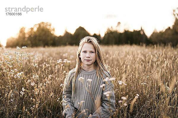 Blond girl with long blond hair standing at wildflower field
