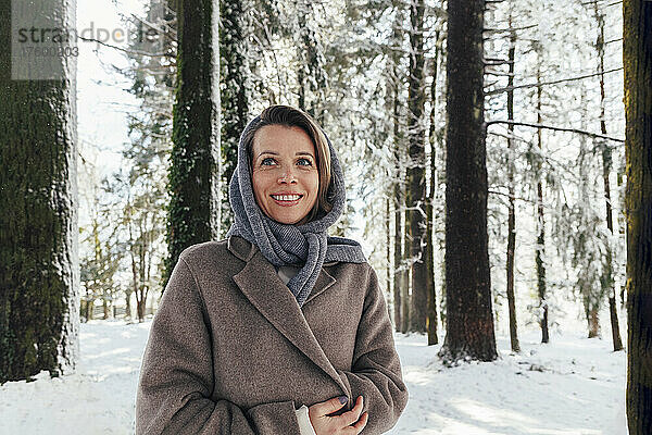 Lächelnde Frau steht im Winterwald
