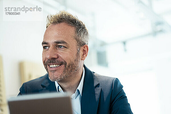 Smiling businessman using tablet PC at workplace