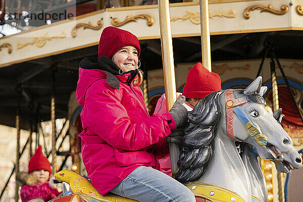 Lächelndes Mädchen genießt Karussellfahrt auf dem Weihnachtsmarkt