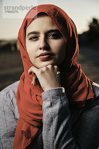 Junge Frau mit Hand am Kinn und Hijab