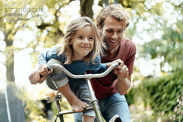 Glücklicher Vater  der seinen Sohn mit dem Fahrrad mitnimmt