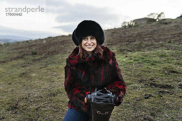 Lächelnde Frau mit Pelzmütze auf der Ranch