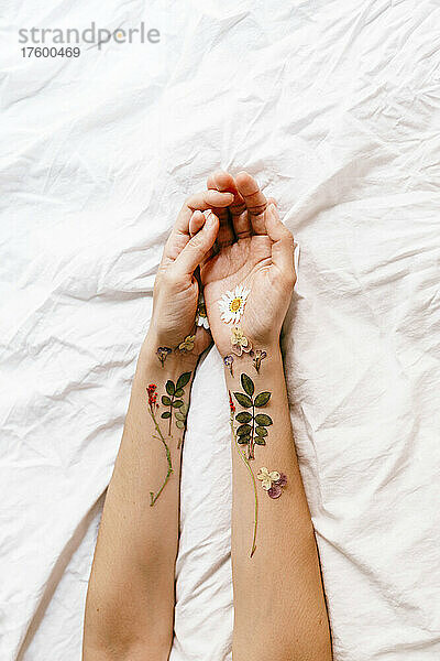 Frauenhände mit Blumenarrangement auf dem Bett