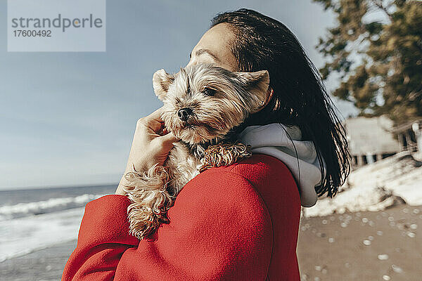 Junge Frau mit Yorkshire-Terrier am Strand