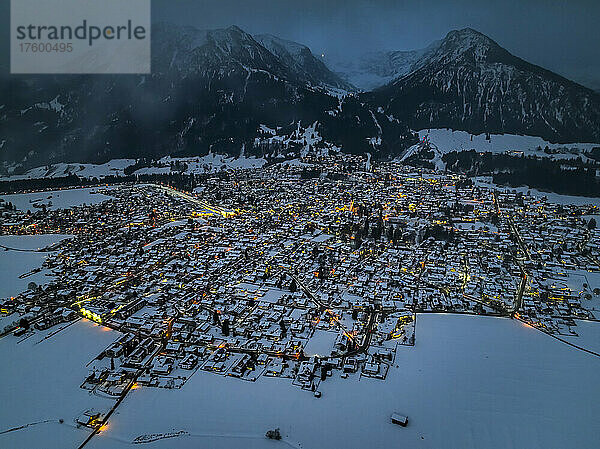 Germany  Bavaria  Oberstdorf  Helicopter view of snow covered town in Allgau Alps at dusk