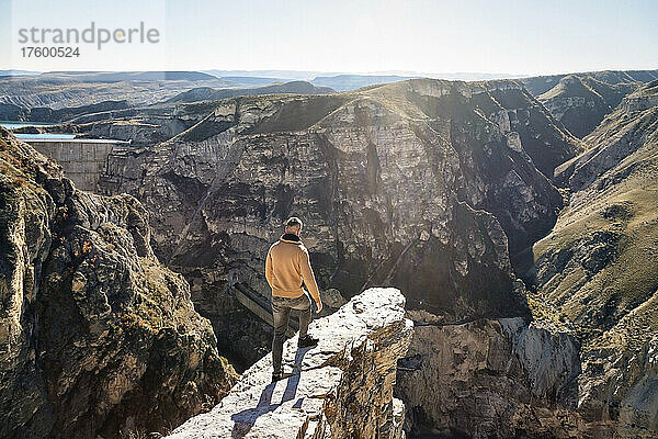Mann steht an einem sonnigen Tag auf einem Berg