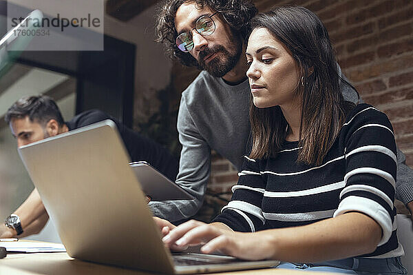 Geschäftsmann und Geschäftsfrau diskutieren am Laptop im Coworking-Büro