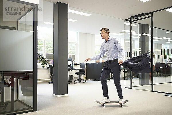 Geschäftsmann fährt Skateboard im modernen Büro