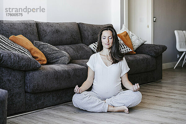 Schwangere Frau meditiert zu Hause