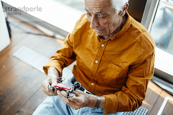 Älterer Mann sitzt mit Drohne am Hausboot