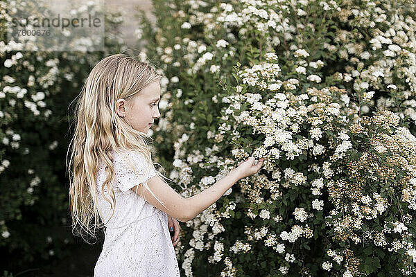Blondes Mädchen berührt weiße Blumen