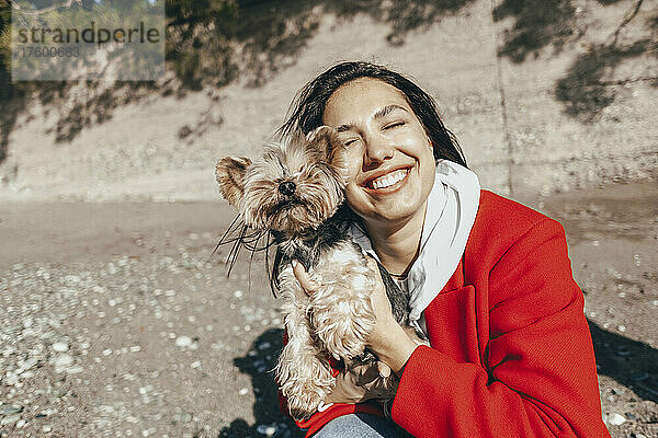 Lächelnde Frau mit Yorkshire-Terrier am Strand