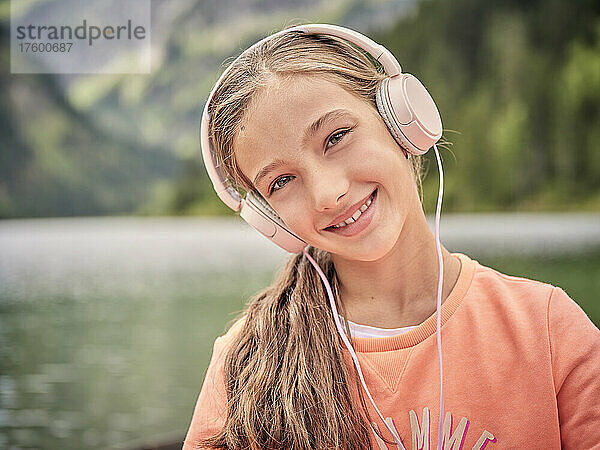 Lächelndes Mädchen  das über Kopfhörer Musik hört