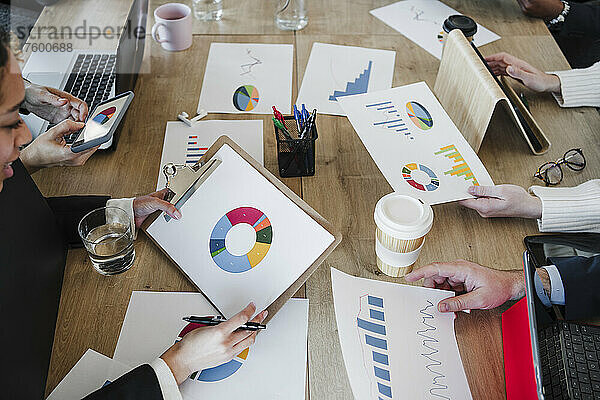Geschäftsleute und Geschäftsfrauen mit Grafiken und Diagrammen  die gemeinsam im Büro eine Strategie planen