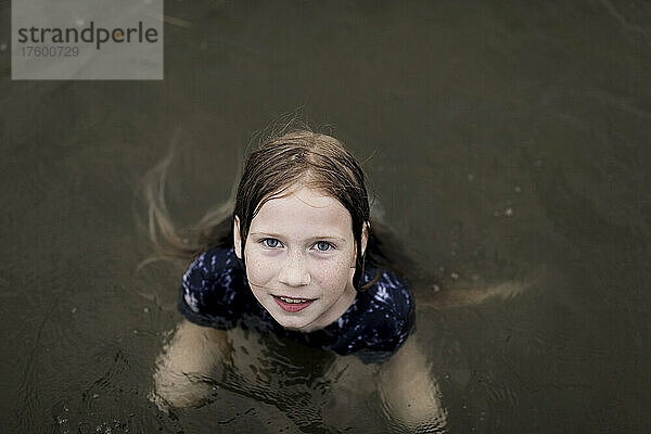 Mädchen mit braunen Haaren schwimmt im Seewasser
