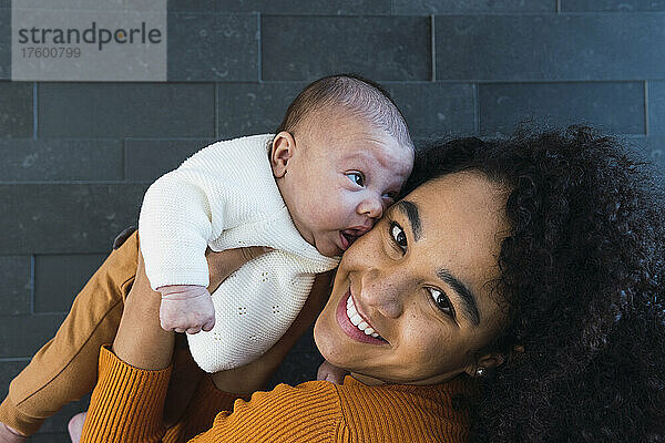 Lächelnde Mutter mit Baby an der Wand