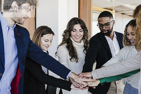 Multiethnische Geschäftskollegen stapeln sich im Coworking-Büro die Hände