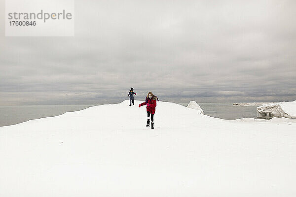 Schwestern spielen im Winter im Schnee am See