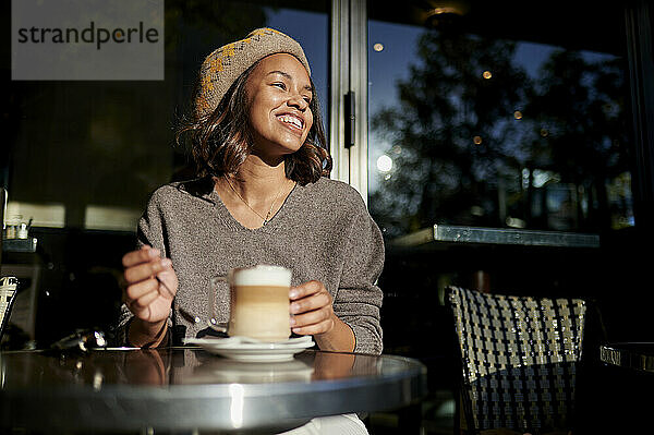 Junge Frau mit Kaffee lacht im Straßencafé