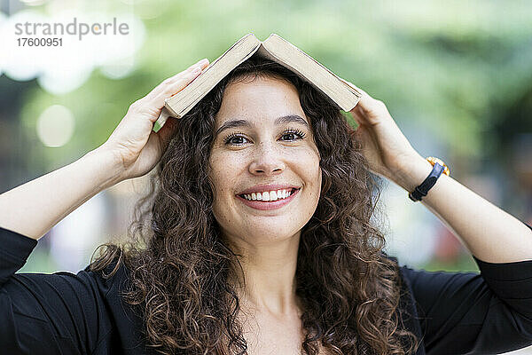 Smiling woman holding open book on head