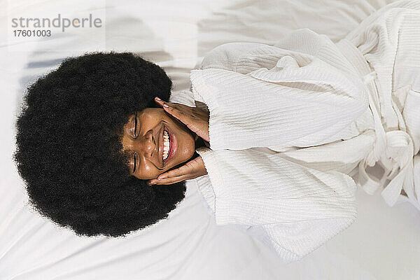 Glückliche Afro-Frau liegt mit geschlossenen Augen zu Hause im Bett