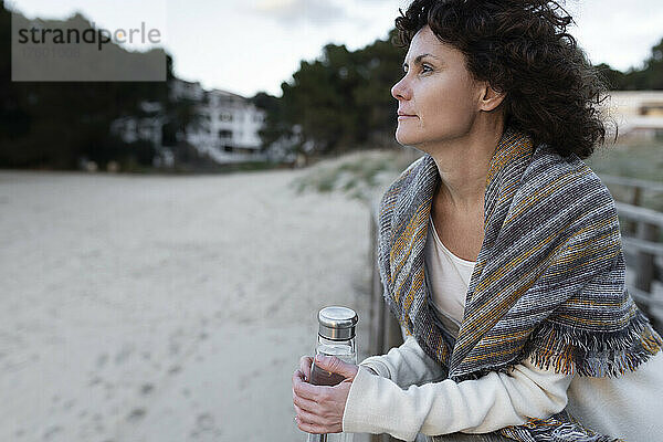 Frau mit Wasserflasche am Strand im Winter