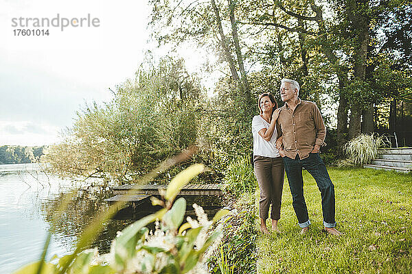 Älterer Mann und Frau stehen am See im Garten