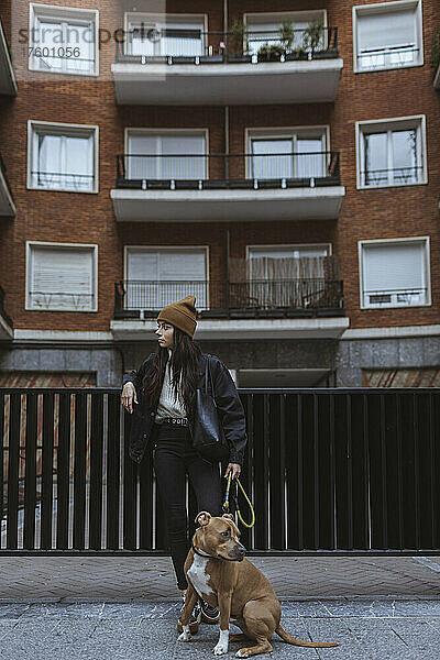 Junge Frau mit Hund steht vor dem Tor