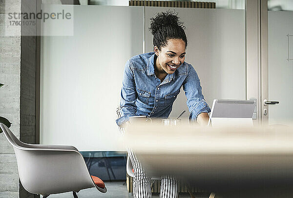 Lächelnde Geschäftsfrau  die im Büro am Tablet-PC arbeitet