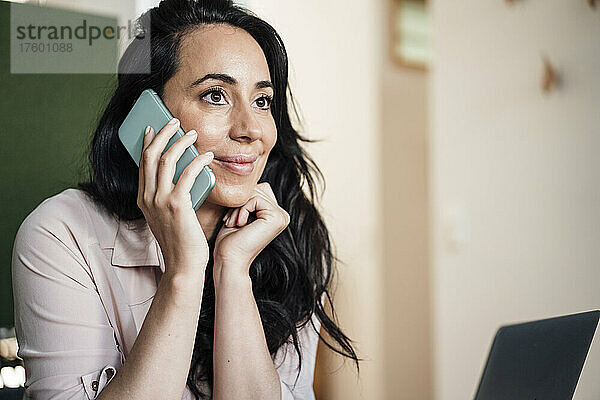 Geschäftsfrau spricht im Büro mit Smartphone