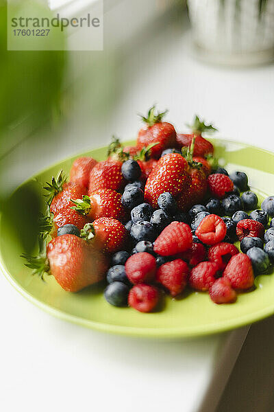 Teller mit Blaubeeren  Himbeeren und Erdbeeren auf dem Tisch