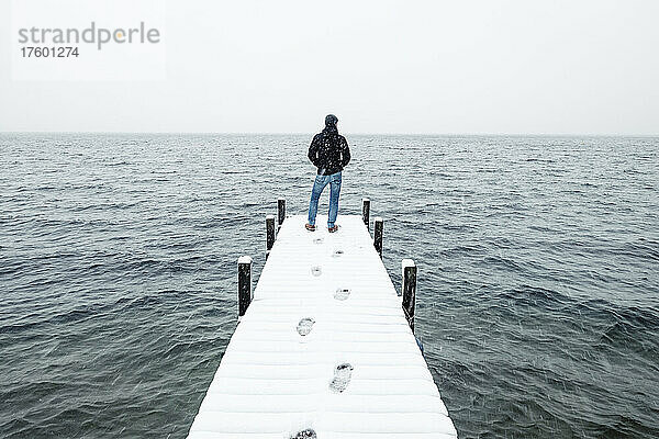 Wanderer bewundert den See  der im Winter auf einem schneebedeckten Steg steht  Walchensee  Bayern  Deutschland