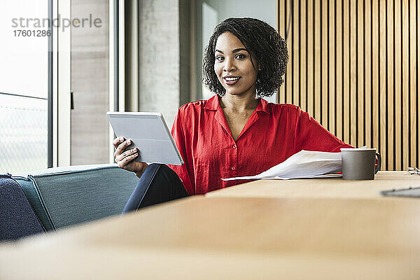 Junge Geschäftsfrau mit Tablet-Computer und Kaffee auf dem Schreibtisch am Arbeitsplatz