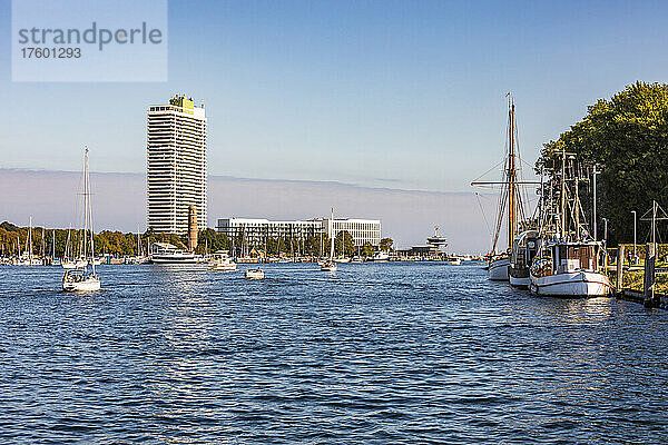 Deutschland  Schleswig-Holstein  Travemünde  Boote auf der Trave mit hohem Wohnhaus im Hintergrund