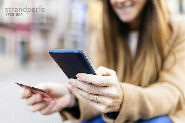 Frau mit Debitkarte tätigt Online-Zahlung per Smartphone