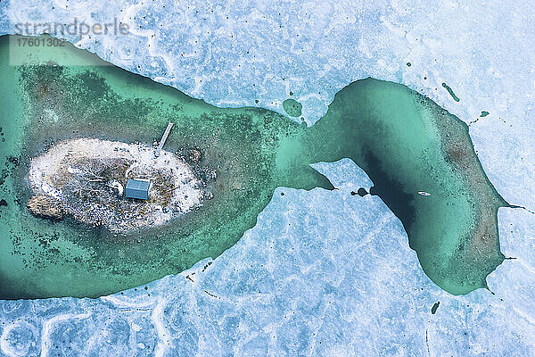 Germany  Bavaria  Aerial view of lone man paddleboarding between ice floes in turquoise Eibsee lake