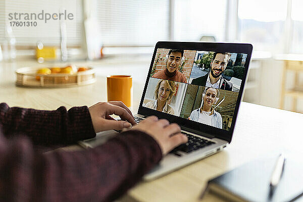 Working woman doing video conference with business colleagues on laptop at home