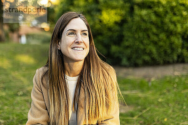Lächelnde Frau mit braunen Haaren im Park