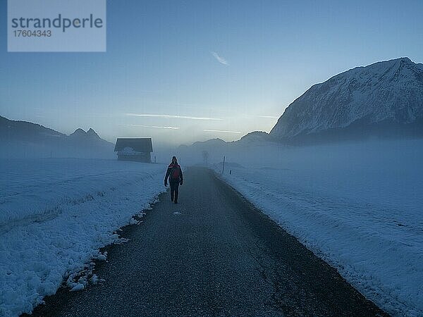 Winterlandschaft  Wanderin geht im Morgennebel auf einsamer Straße  Bad Mitterndorf  Steiermark  Österreich  Europa