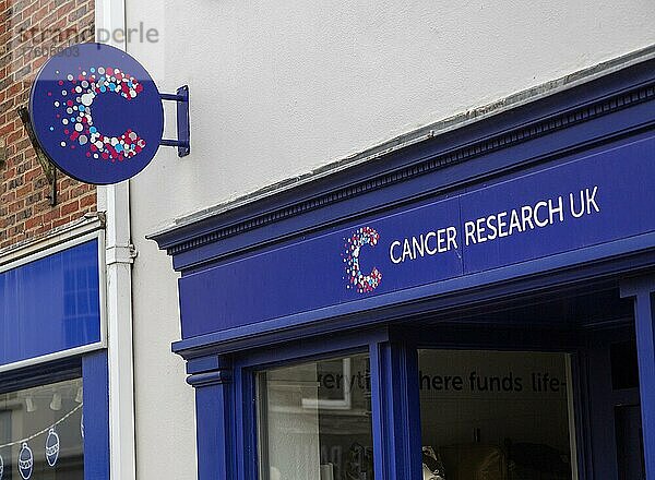 Schilder des Wohltätigkeitsladens von Cancer Research UK vor einem Geschäft in der High Street  UK